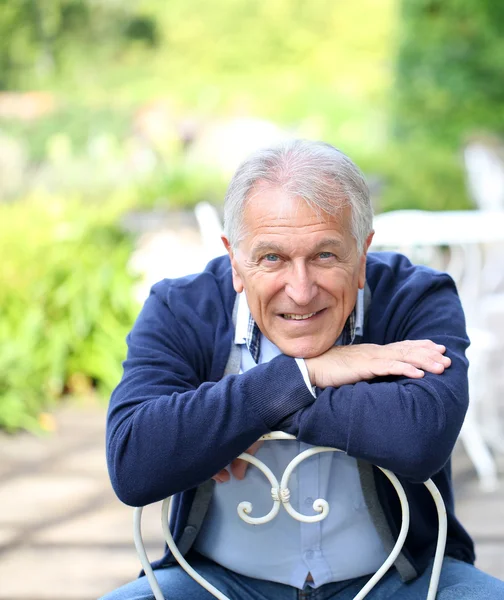 Senior sitzt im heimischen Garten — Stockfoto