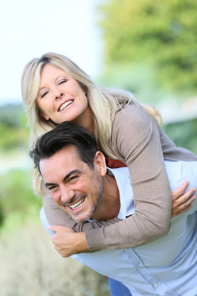 Man geven piggyback rit naar vrouw — Stockfoto