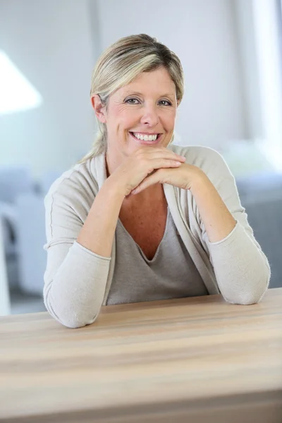 Sorrindo mulher confiante sentada à mesa — Fotografia de Stock