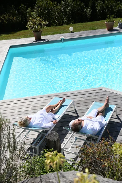 Couple relaxing by swimming pool — Stock Photo, Image