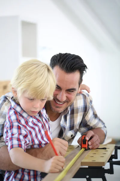 Father with kid measuring wood plank — Stock Photo, Image