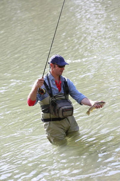 Pescador pescando trucha de fario en el río — Foto de Stock