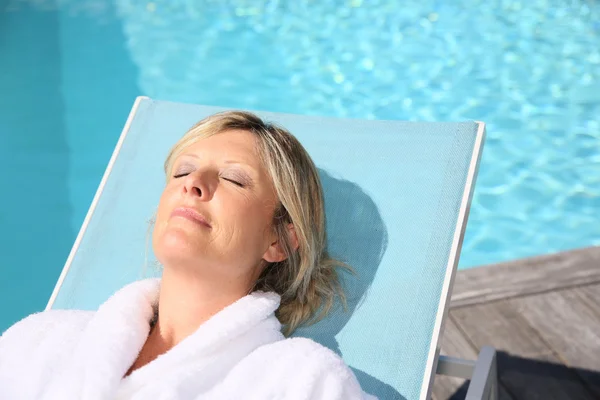 Mujer relajante en silla larga junto a la piscina — Foto de Stock