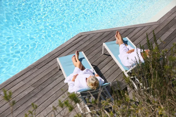 Couple relaxing by swimming pool — Stock Photo, Image