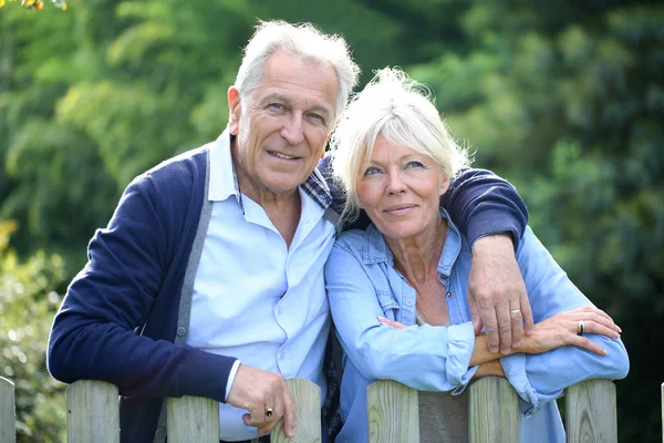 Senior couple standing by fence — Stock Photo, Image