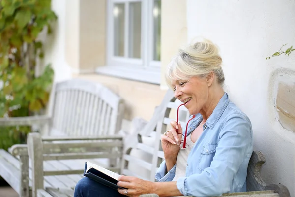 Mujer mayor leyendo libro en el banco —  Fotos de Stock