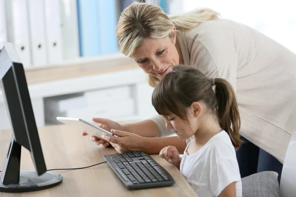 Teacher with girl using computer and tablet — Stock Photo, Image