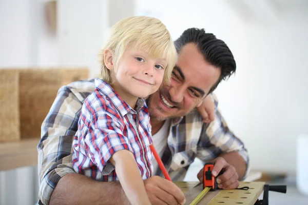 Padre con niño midiendo tablón de madera —  Fotos de Stock