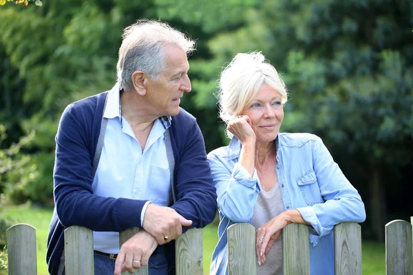 Senior couple standing by fence — Stock Photo, Image