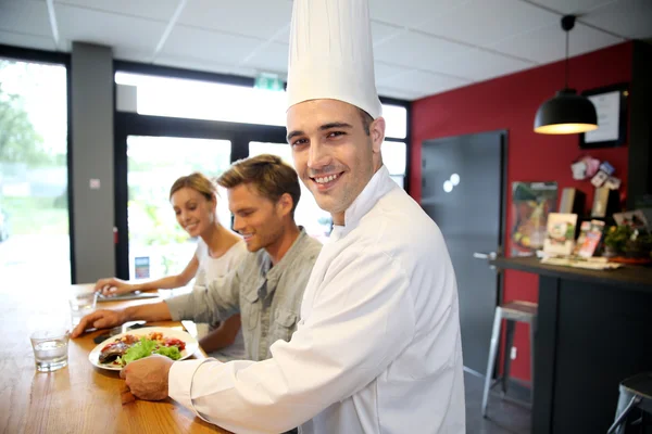 Smilende kokk serverer kunder – stockfoto