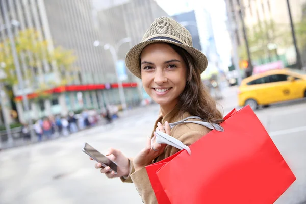 Menina de compras com saco e smartphone — Fotografia de Stock
