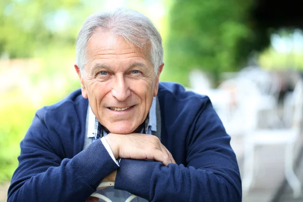 Senior man sitting in home garden — Stock Photo, Image