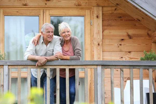Couple standing oustide log cabin — Stock Photo, Image
