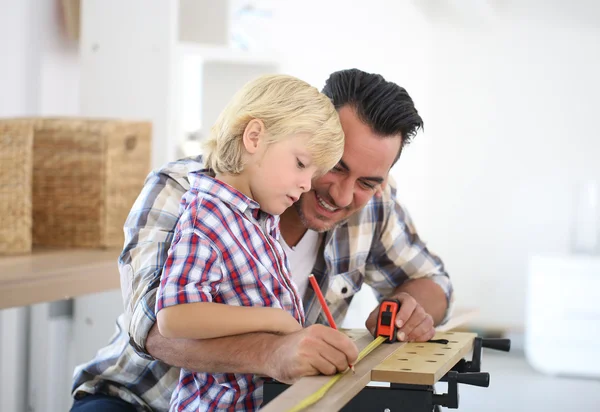 Father with kid measuring wood plank — Stock Photo, Image