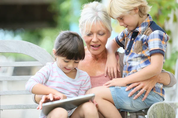 Бабуся з дітьми грає на планшеті — стокове фото