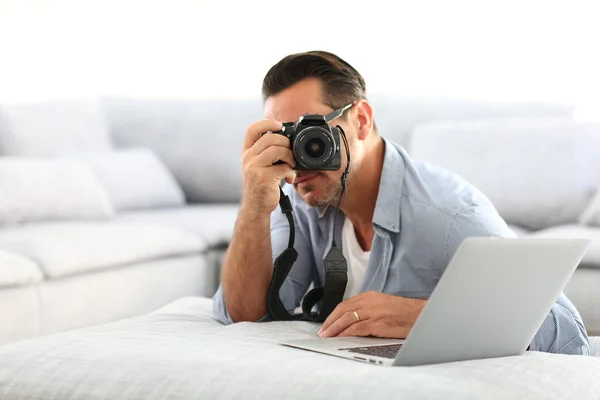 Mann benutzt Spiegelreflexkamera und Laptop — Stockfoto