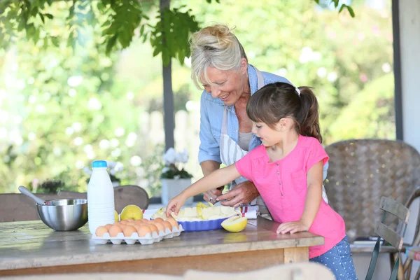 Grandmother cooking pie with little girl — Stock Photo, Image