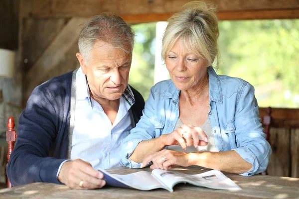 Couple in yard reading magazine — Stock Photo, Image