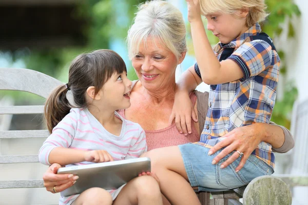 Abuela con niños jugando en la tableta —  Fotos de Stock