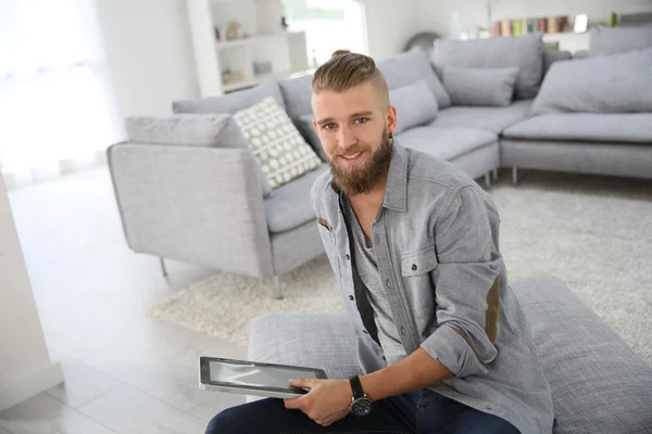 Homem sittign na sala de estar com tablet — Fotografia de Stock