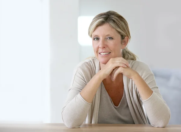 Femme confiante et souriante assise à table — Photo