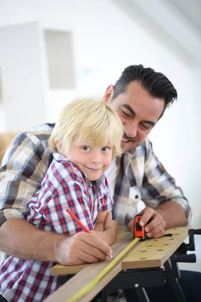 Padre con niño midiendo tablón de madera —  Fotos de Stock