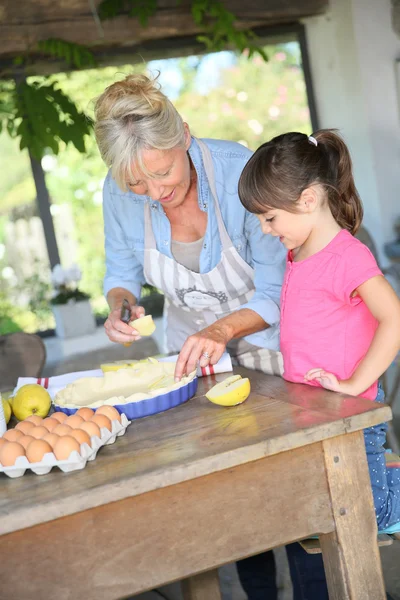 Grandmother cooking pie with little girl — Stock Photo, Image