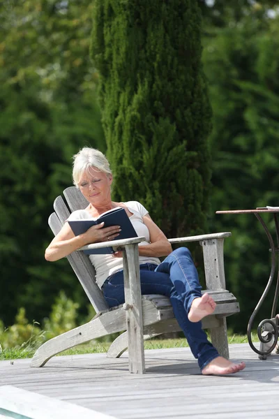 Frau liest Buch im Hinterhof Stockbild