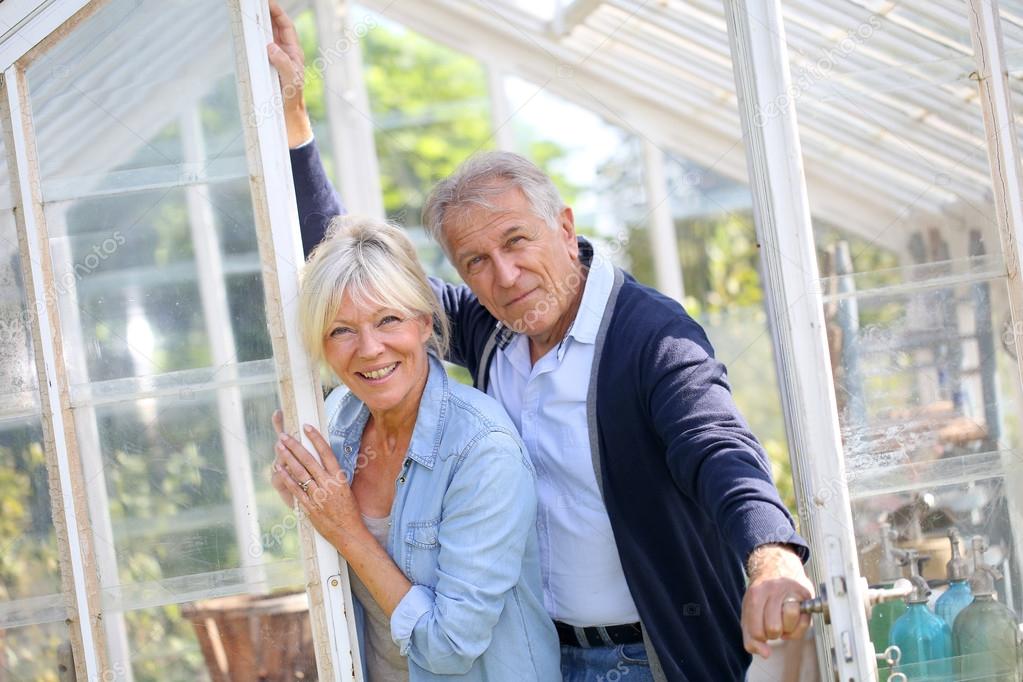 Couple standing by greenhouse in garden