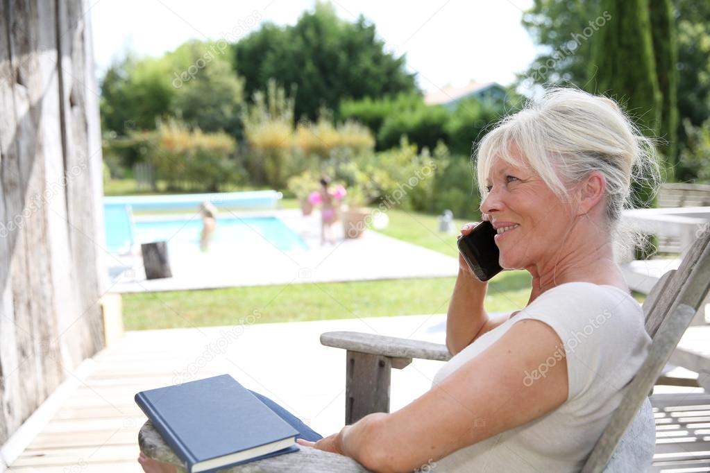 Woman talking on phone by swimming-pool