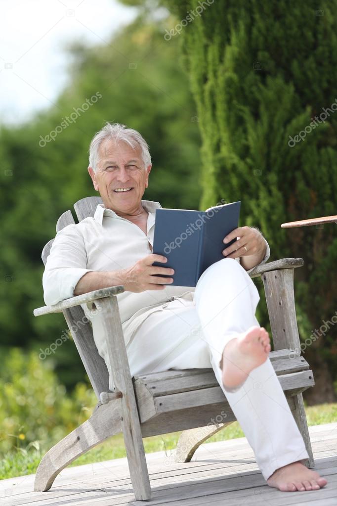 Man reading book in pool deck chair