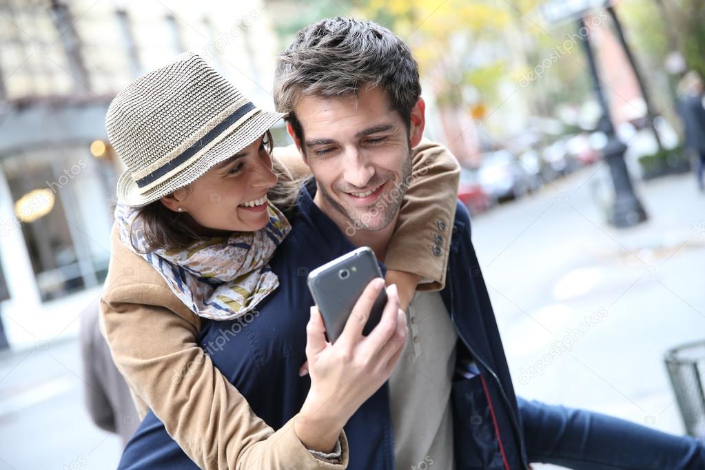 Cheerful couple playing with smartphone