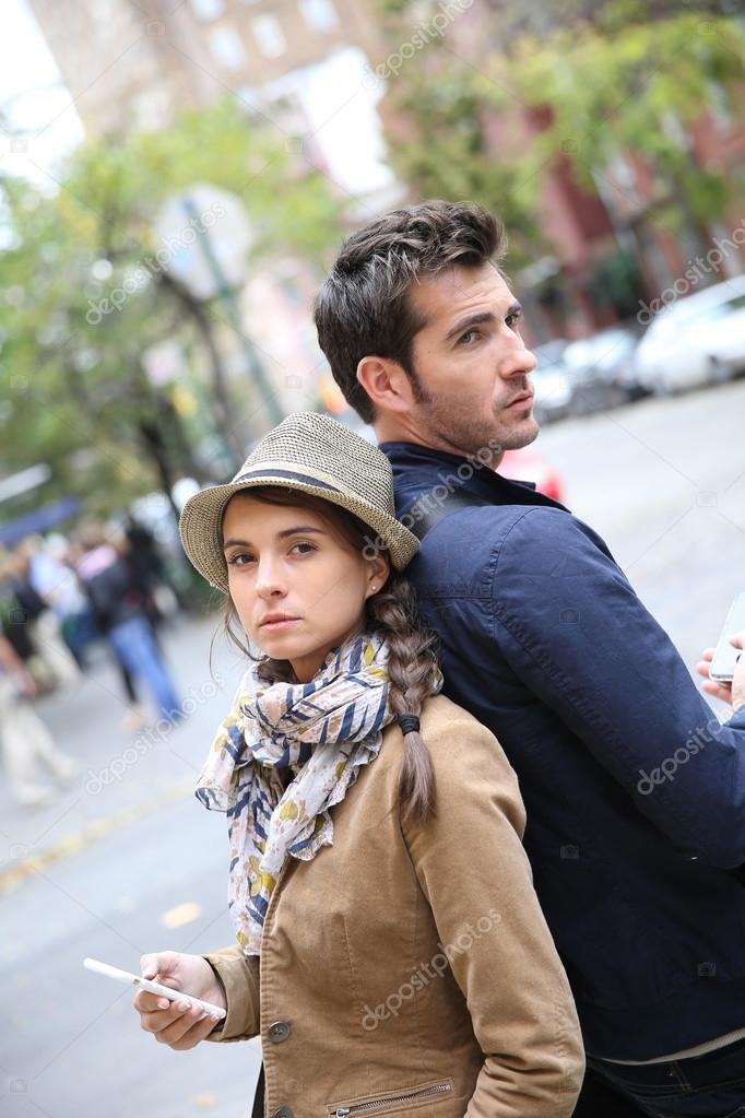 Couple standing back to back in street