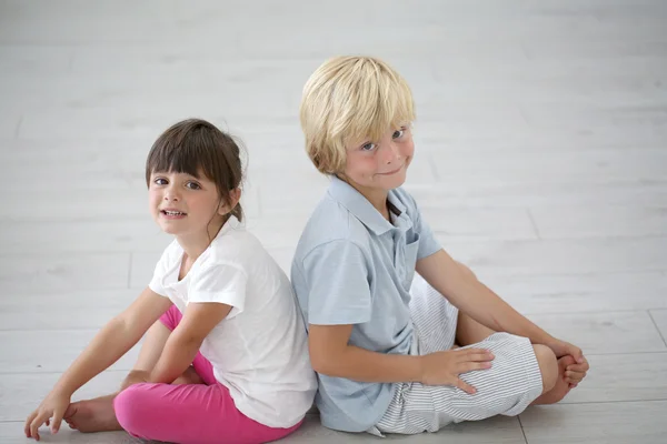 Hermano y hermana sentados espalda con espalda — Foto de Stock