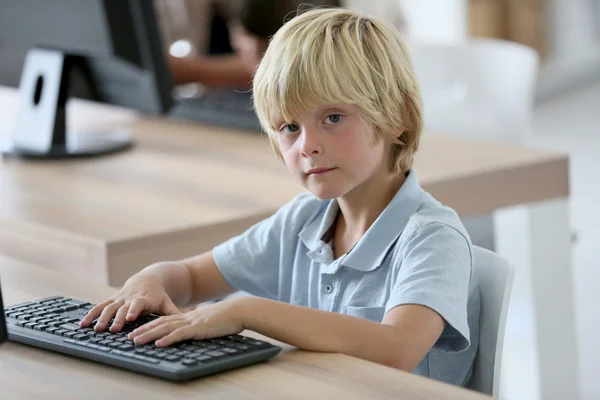 Menino da escola sentado na frente do computador — Fotografia de Stock