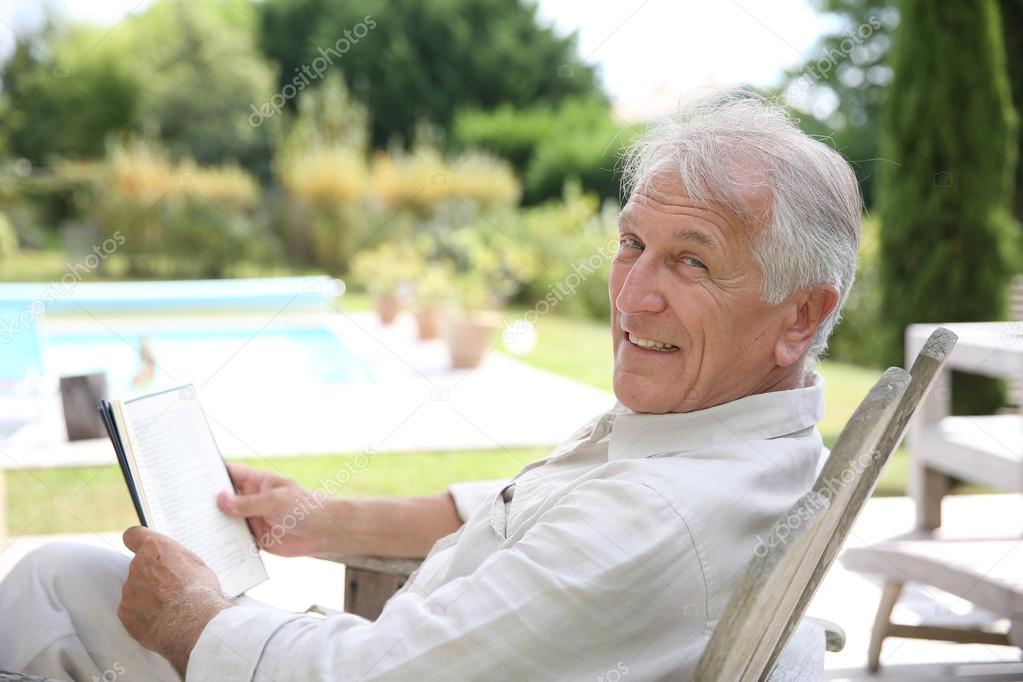 Man reading book in pool deck chair