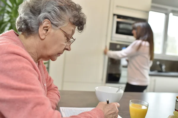 Elderly woman doing crossword — Stock Photo, Image