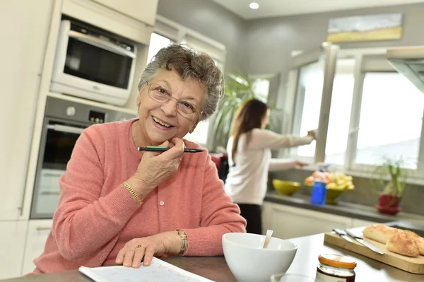 Elderly woman doing crossword — Stock Photo, Image