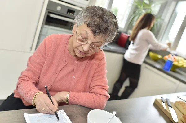 Elderly woman doing crossword — Stock Photo, Image