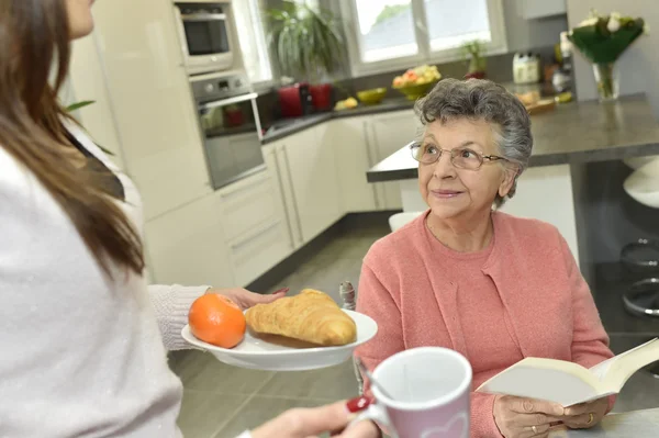 Home helper serving breakfast — Stock Photo, Image