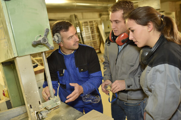 Teacher showing carpentry machinery