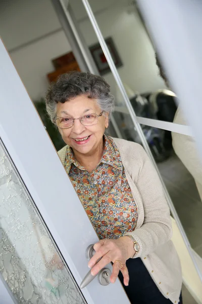 Yaşlı kadın açılış kapı — Stok fotoğraf