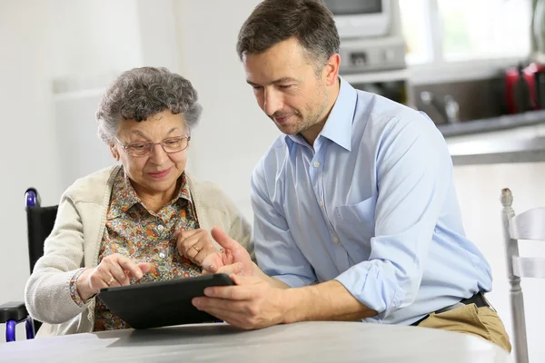 Mann mit älterer Frau mit Tablette — Stockfoto