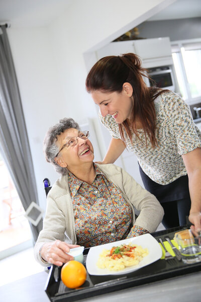 Home carer preparing lunch for woman