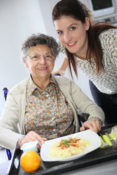 Altenpflegerin bereitet Mittagessen für Frau zu — Stockfoto