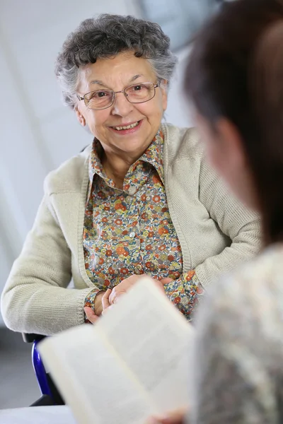 Home carer reading book to woman — Stock Photo, Image