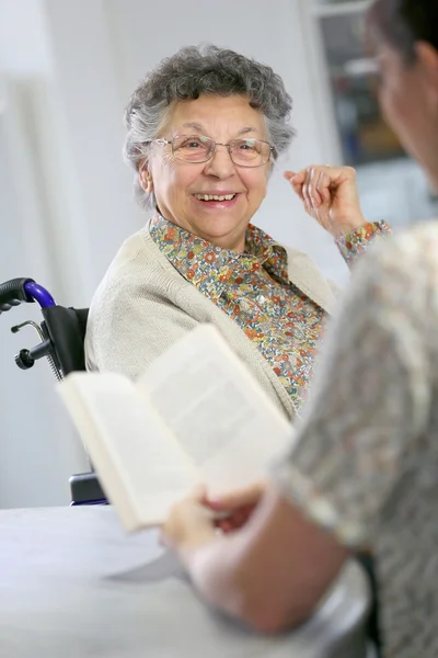 Home carer reading book to woman — Stock Photo, Image