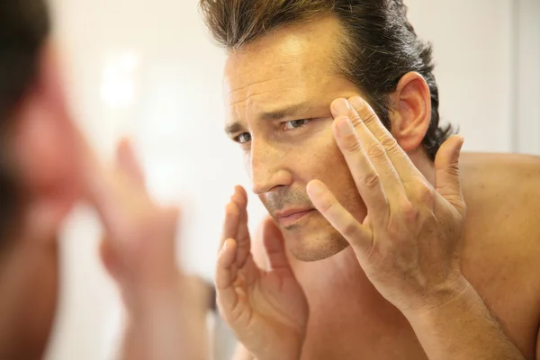 Homem aplicando loção facial — Fotografia de Stock