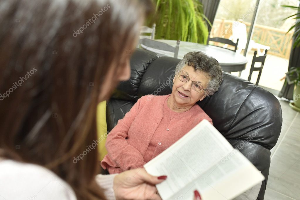 Home carer reading book to woman