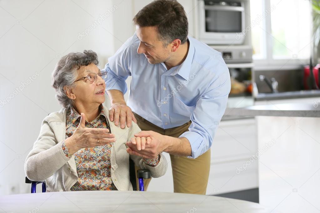 Home carer supporting elderly woman